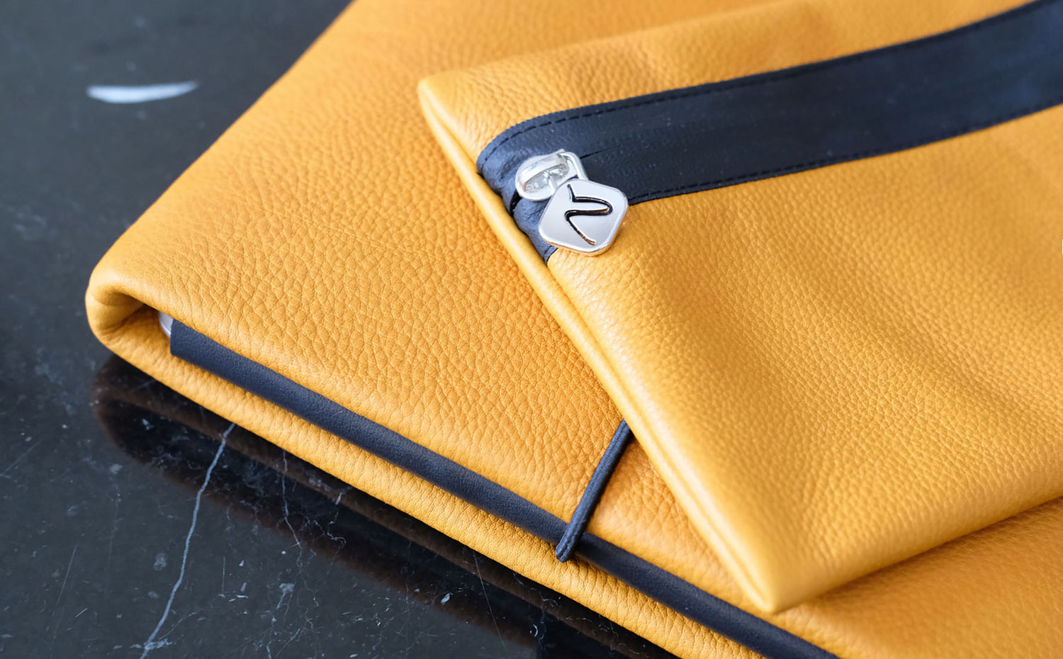 gelbe Kabeltasche aus Leder liegt auf einem passenden Notebookcase von Vandebag