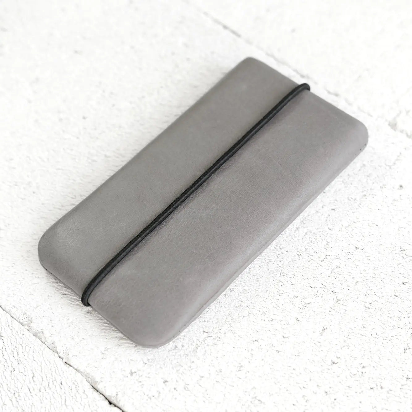 Handyhülle aus Leder liegt seitlich auf Porenbeton