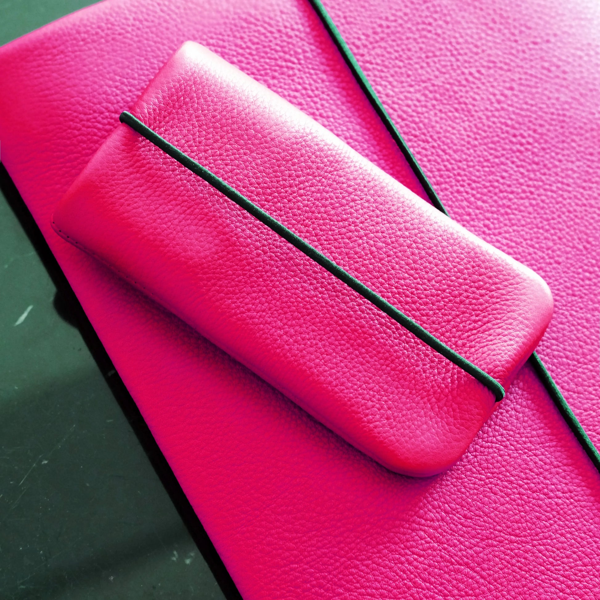iPhone Hülle aus Leder in neonpink liegt aus passender Macbookhülle
