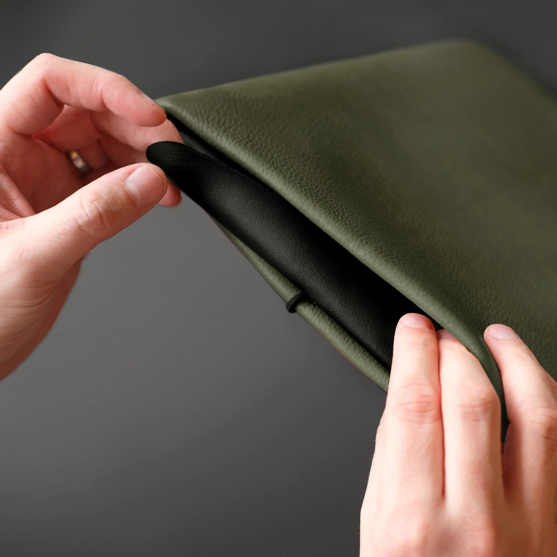 olivgrüne iPadhülle von Vandebag aus Leder wird von zwei Händen mit der Verschlusskordel geschlossen