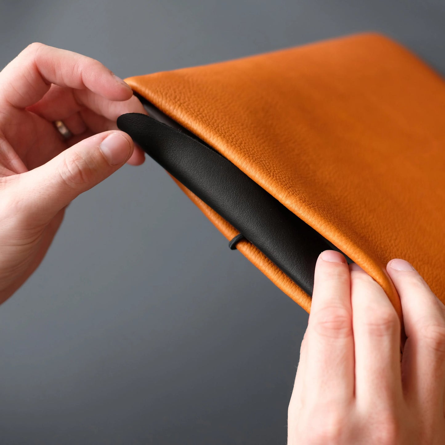 orangefarbene Notebook Hülle mit schwarzer Leder Verschlussklappe
