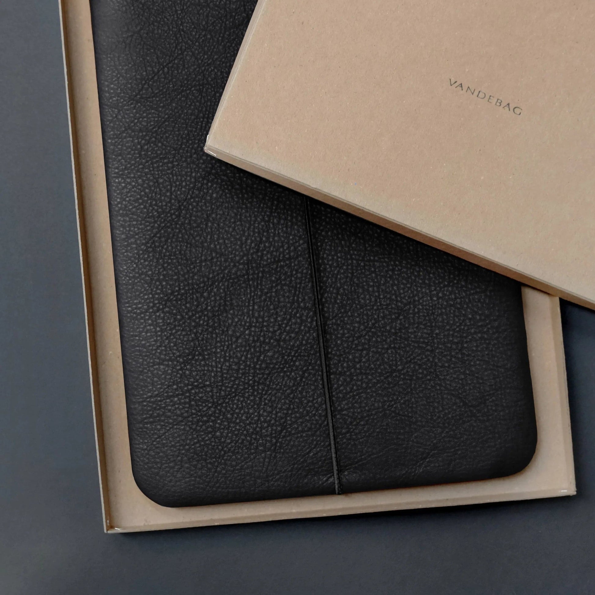 Macbookhülle aus schwarzem Rindsleder liegt in einer Geschenkbox auf der VANDEBAG steht