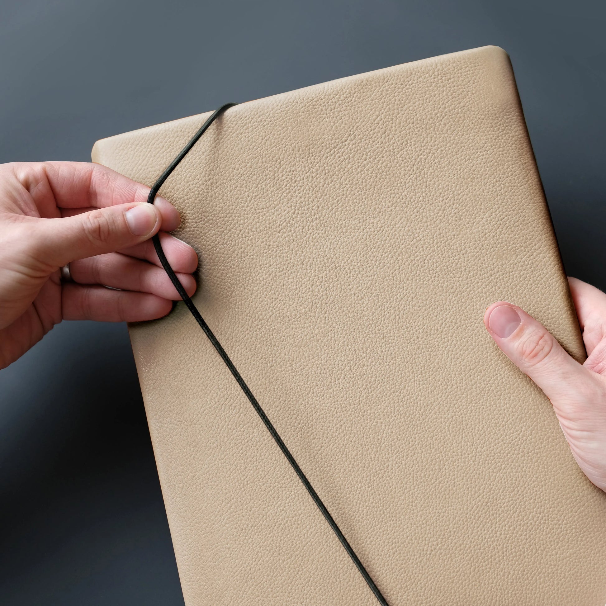 sandfarbene Notebookhülle aus Leder wird mit Gummikordel geschlossen
