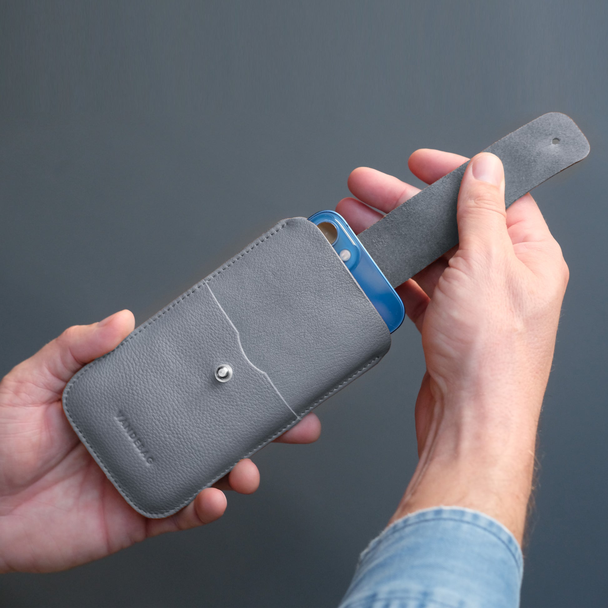 iPhone wird aus grauer Handyhülle mit Lasche gezogen