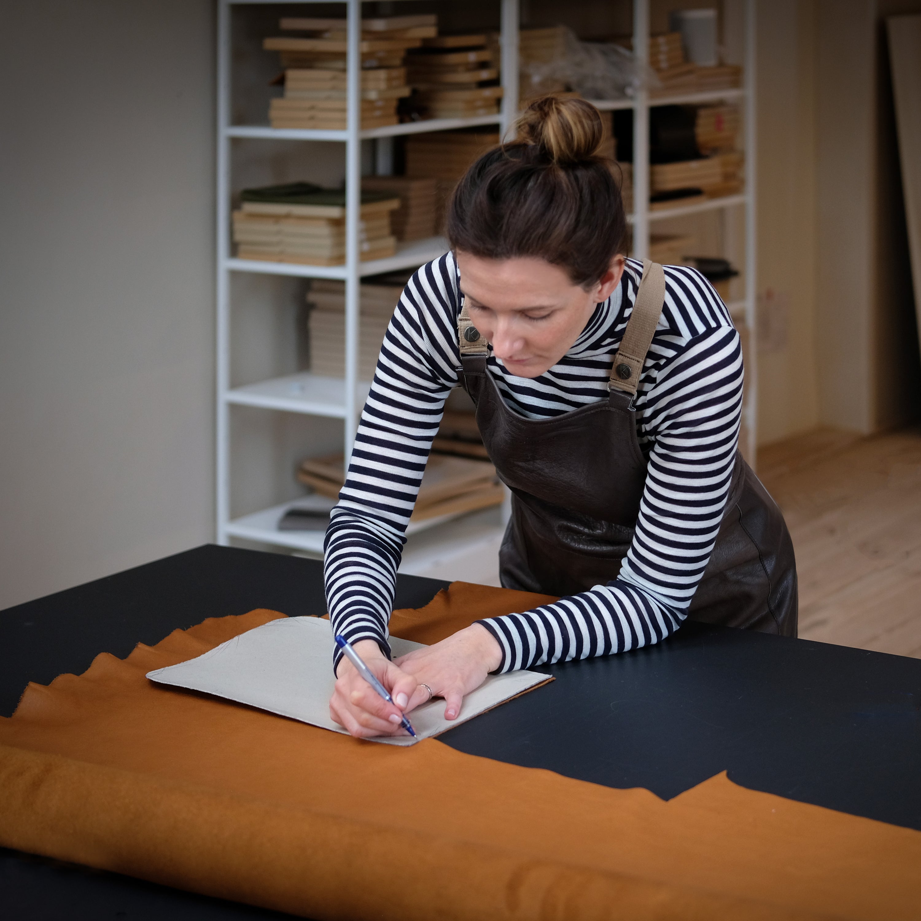Lena von Vandebag arbeitet an einem Schnittisch mit hellbraunem Leder