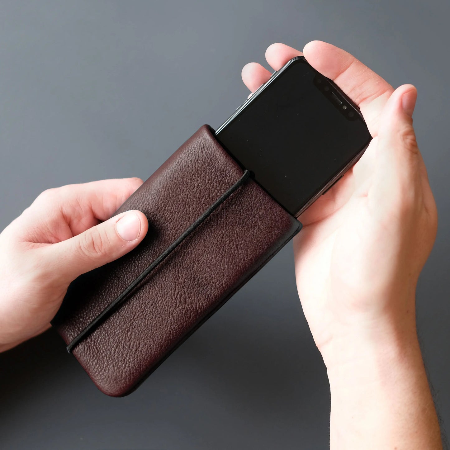 Smartphone wird in eine iPhonehülle aus dunkelbraunem Leder gesteckt