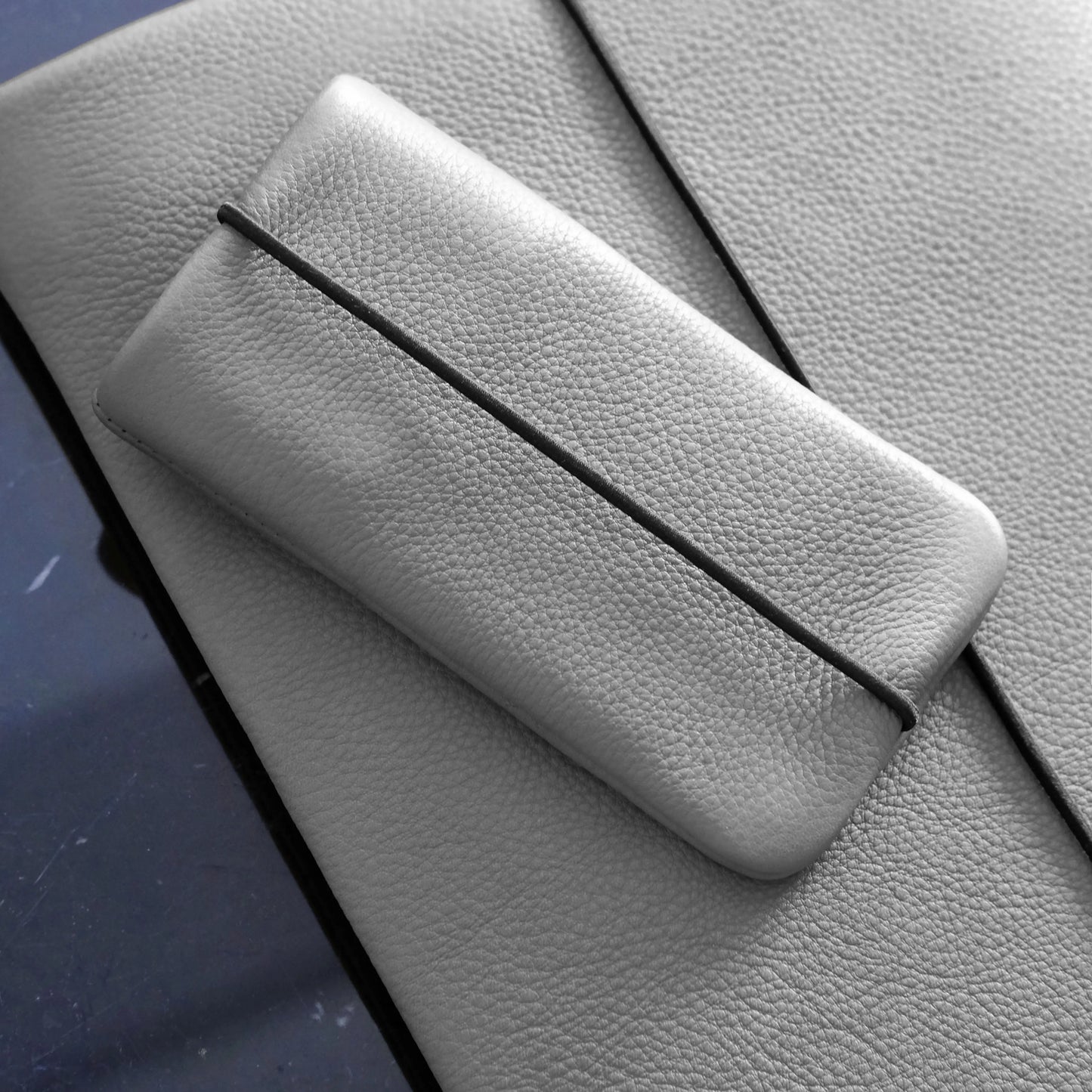 Leder Handyhüllle in grau liegt auf einer passenden grauen Macbookhülle aus Leder