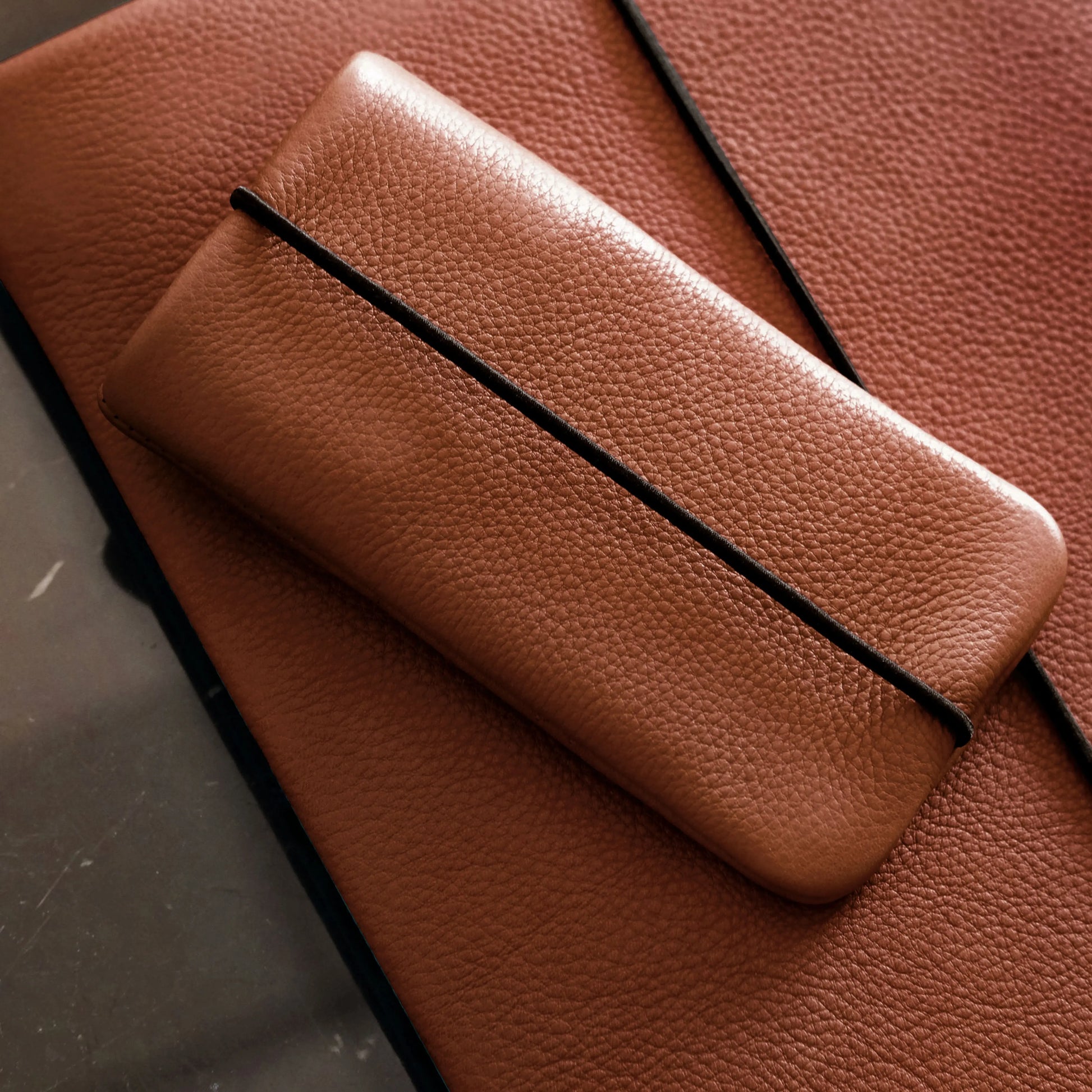 iPhone Case aus braunem Rindsleder liegt auf passender Notebookhülle