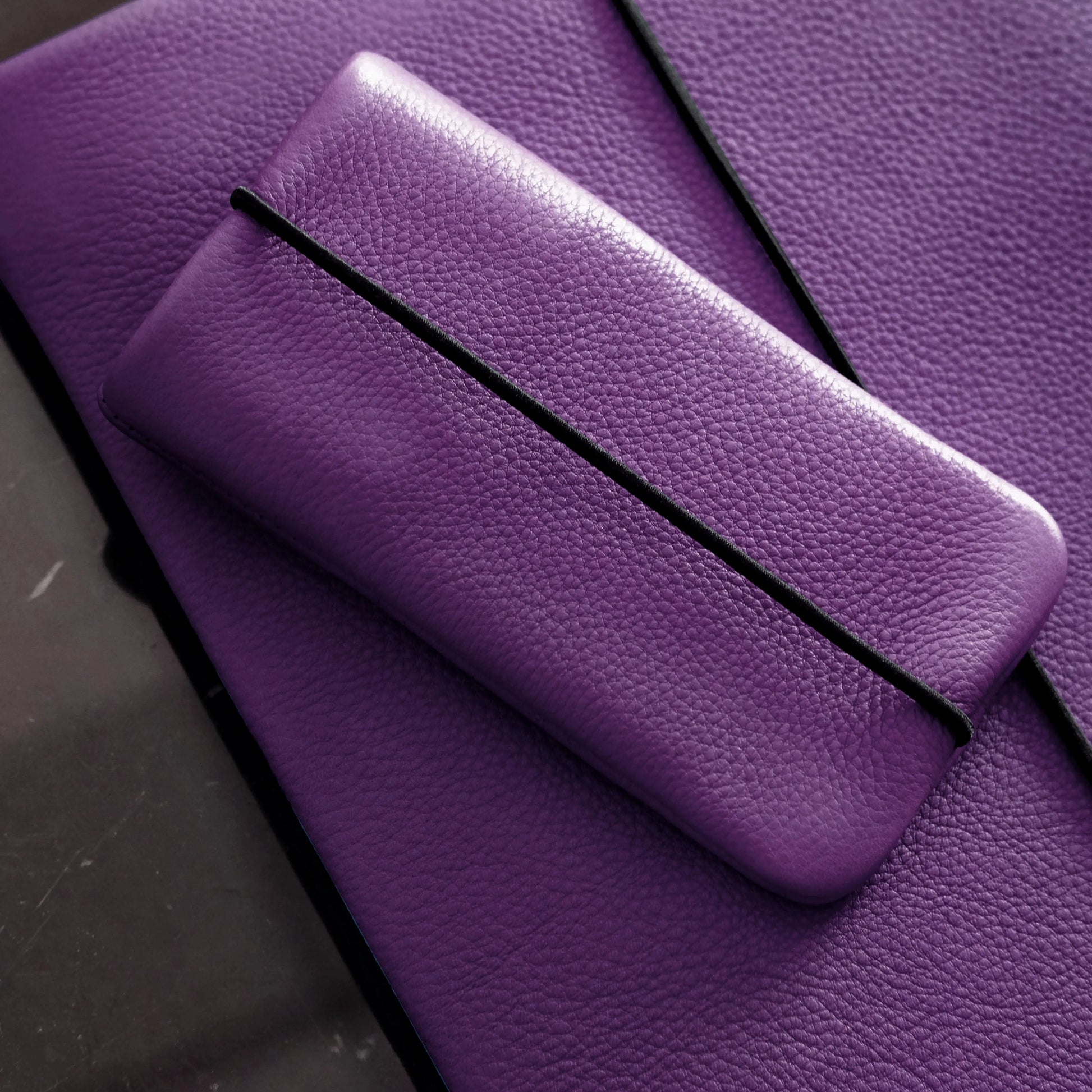 violette iPhonehülle aus Leder liegt auf der passenden Macbookhülle aus Leder