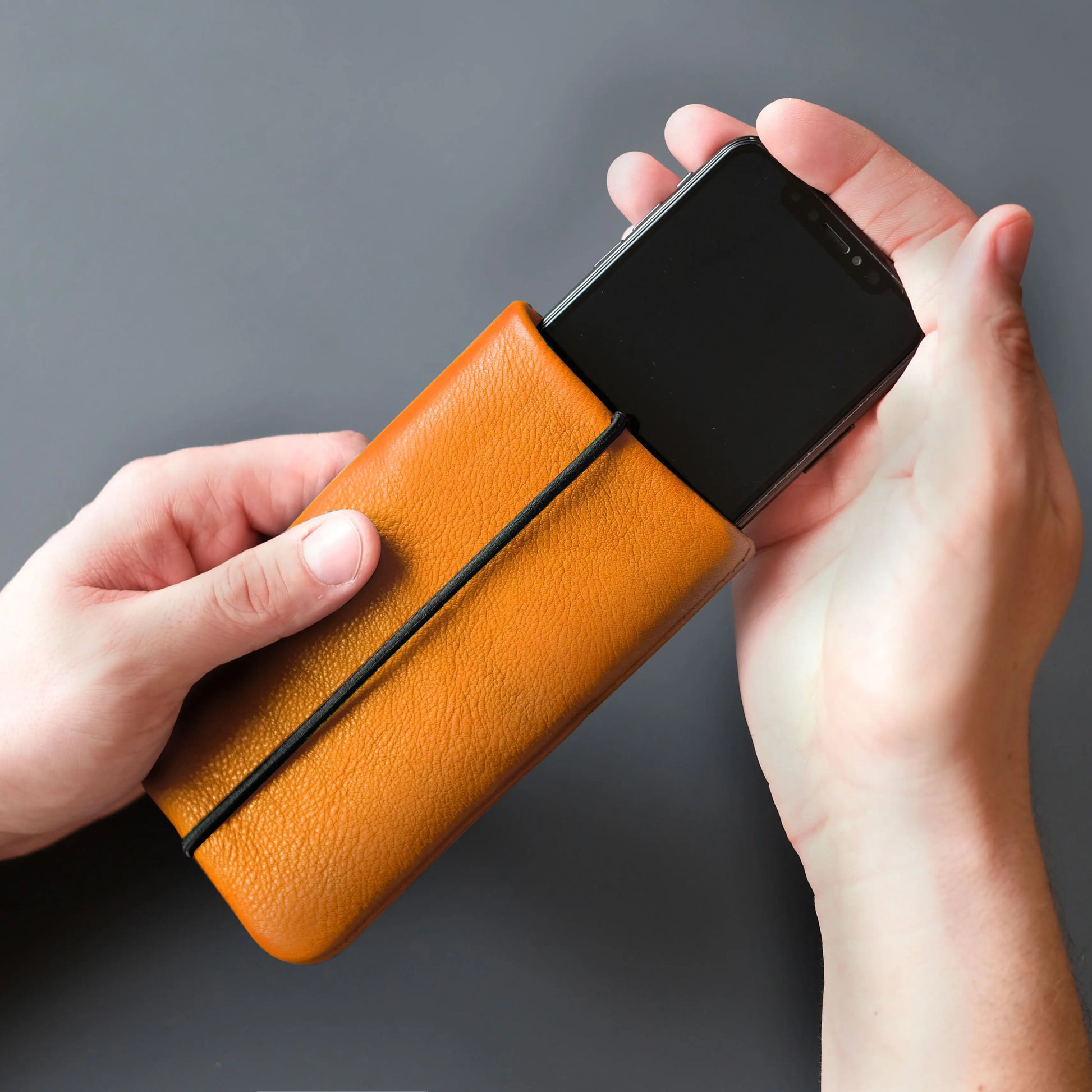 iPhone-Hülle aus orangefarbenem Leder wird mit Smartphone verwendet