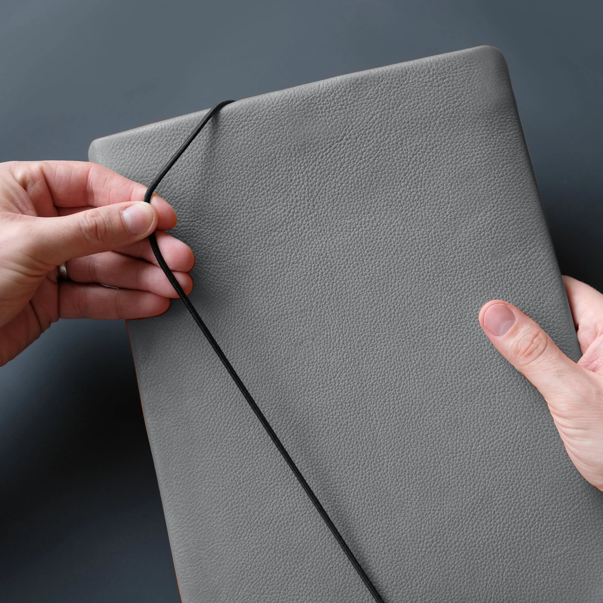 Lederhülle für Notebooks wird mit schwarzem Verschlussgummiband geschlossen