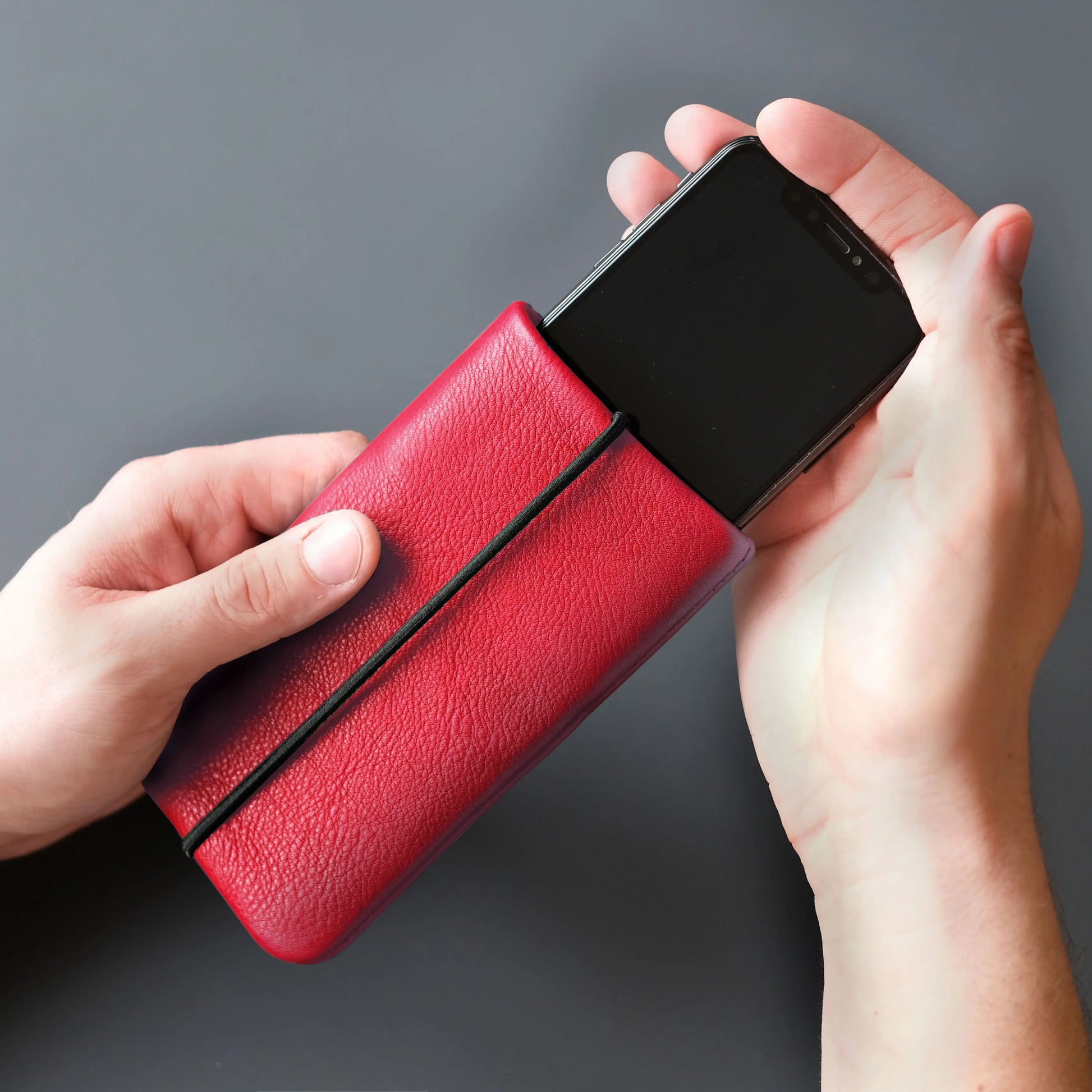 iPhone wird in Handy Hülle aus Leder in rot gesteckt