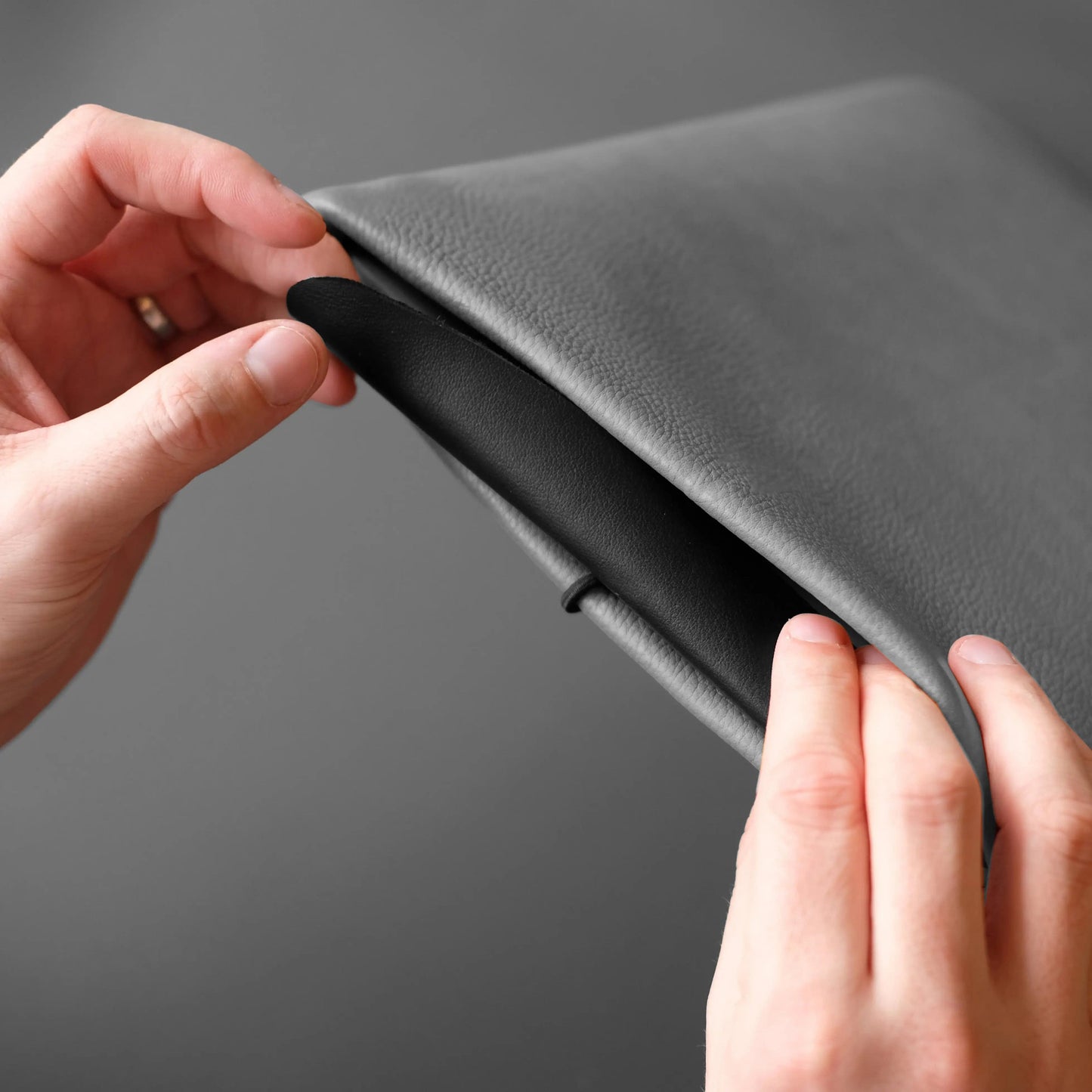 graue Notebookhülle wird mit schwarzer Verschlussklappe geschlossen