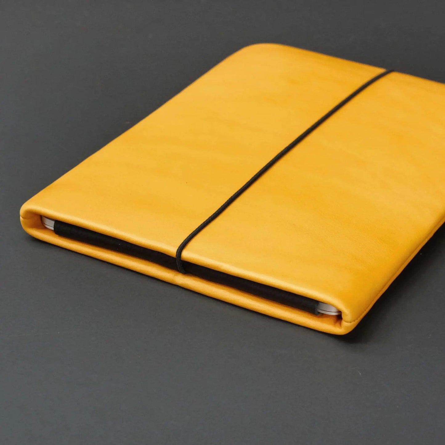 gelbe Lederhülle für Notebooks mit Macbook und schwarzem Verschlussgummi