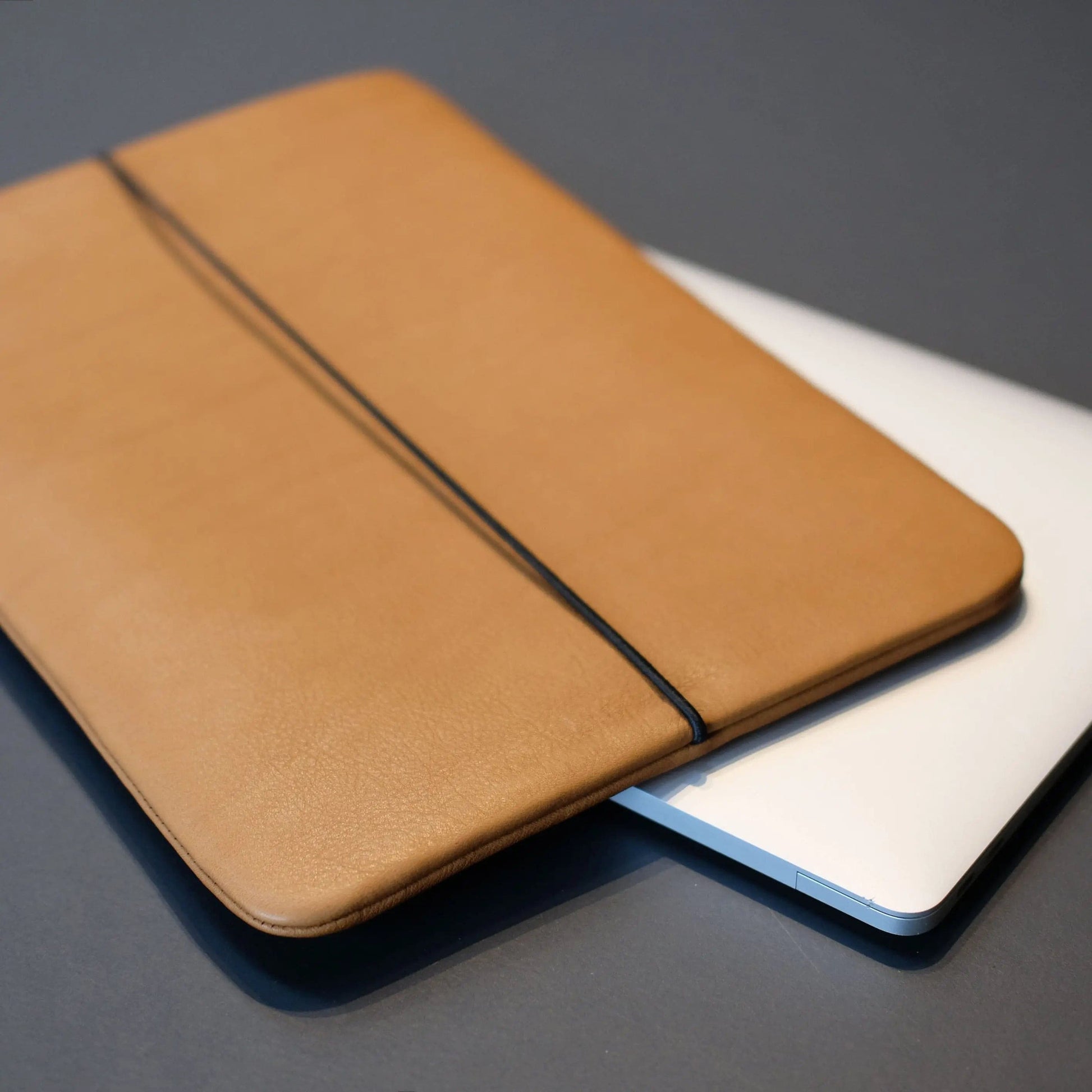 hellbraune Notebookhülle aus Rindsleder liegt auf einem Macbook