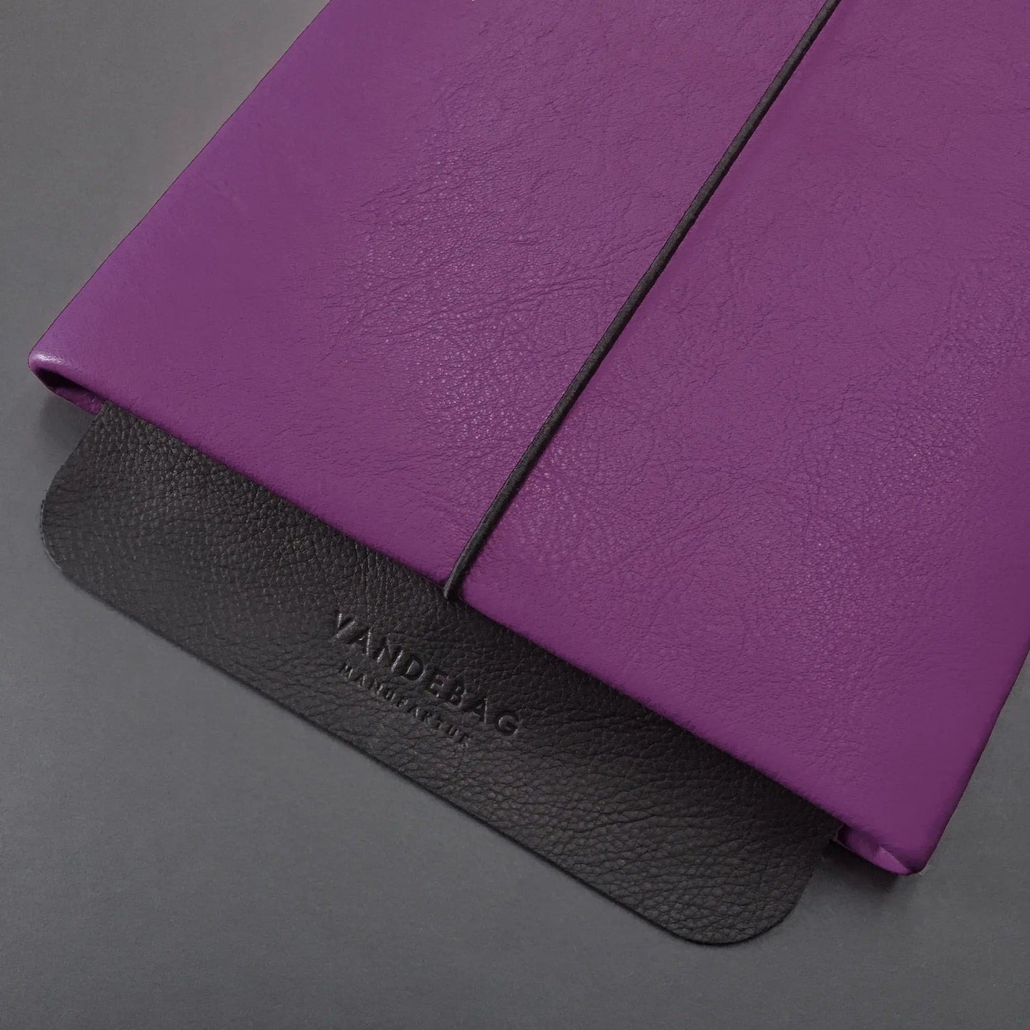 Notebookhülle aus lila Leder mit schwarzer Verschlussklappe aus geprägtem Leder
