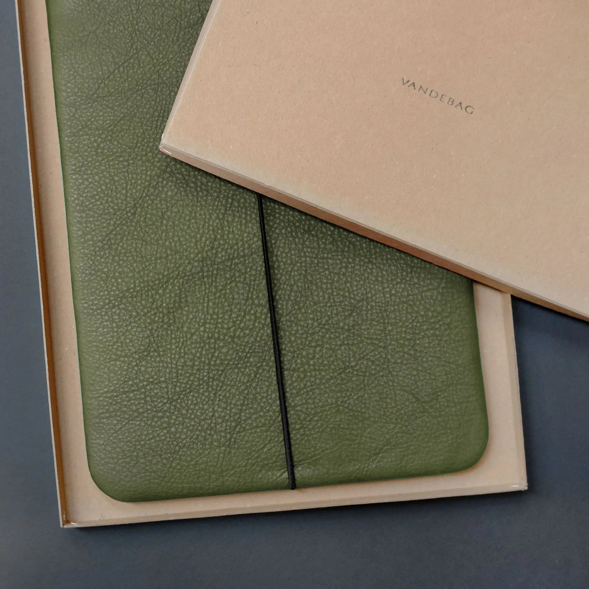 olivgrüne Notebookhülle von Vandebag liegt in Geschenkbox mit Logoprint