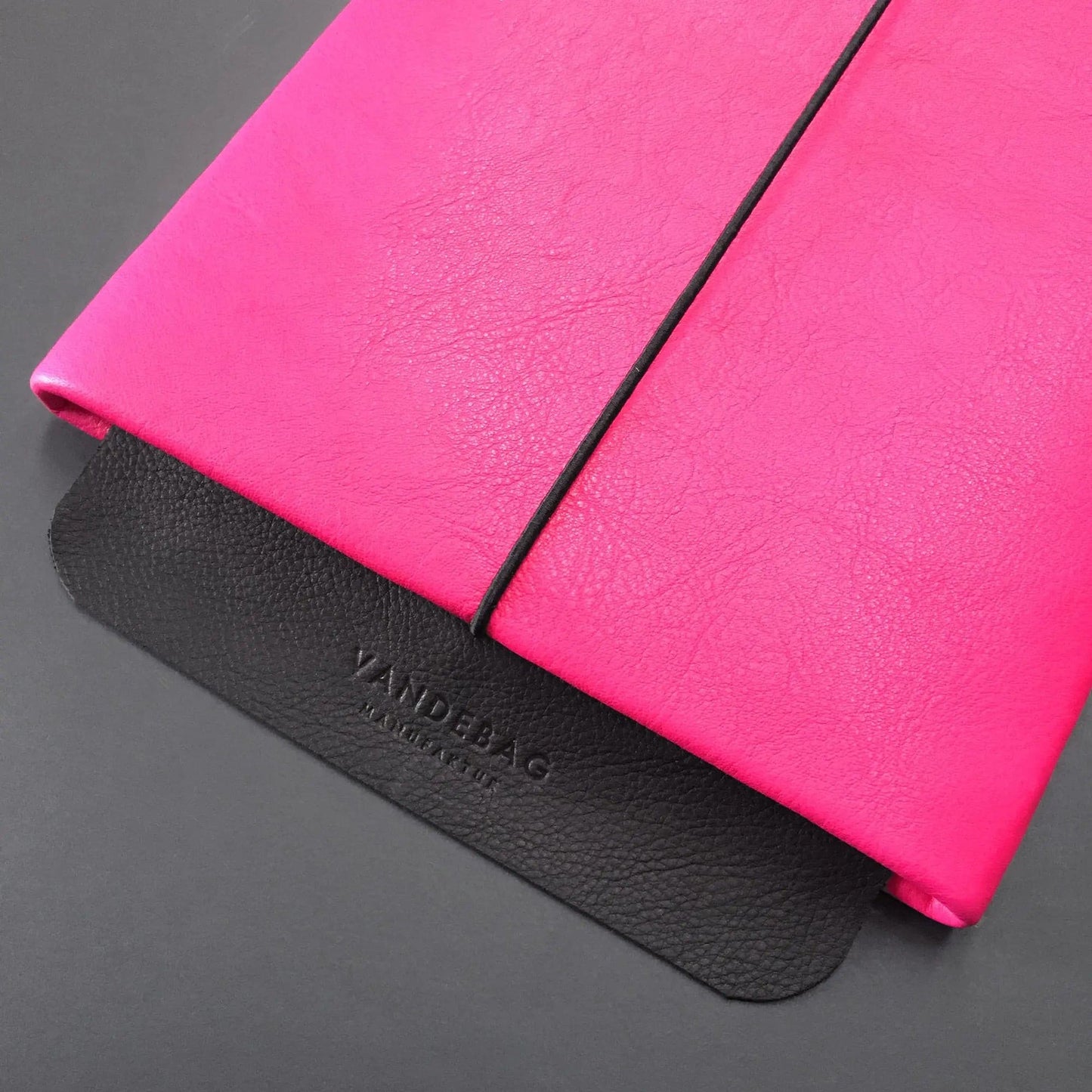neonpinke Leder-Notebookhülle mit schwarzer Verschlussklappe aus geprägtem Leder