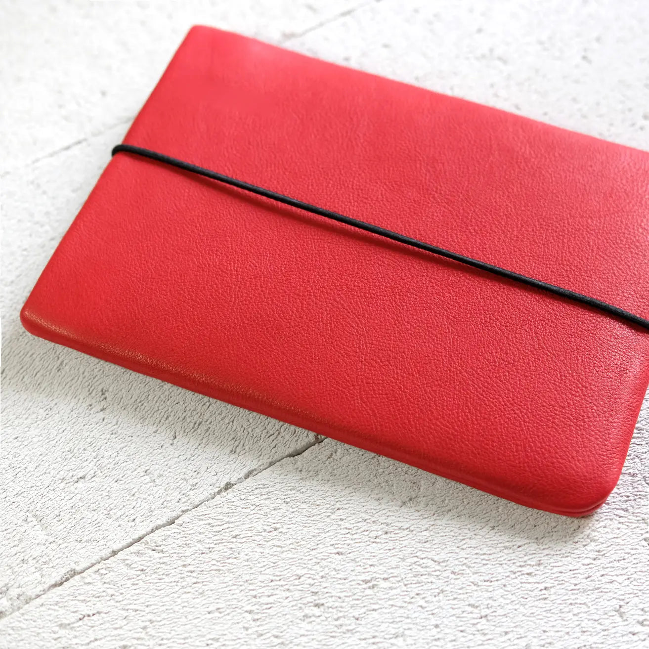 rote Notebook Hülle aus Leder liegt auf Steinboden