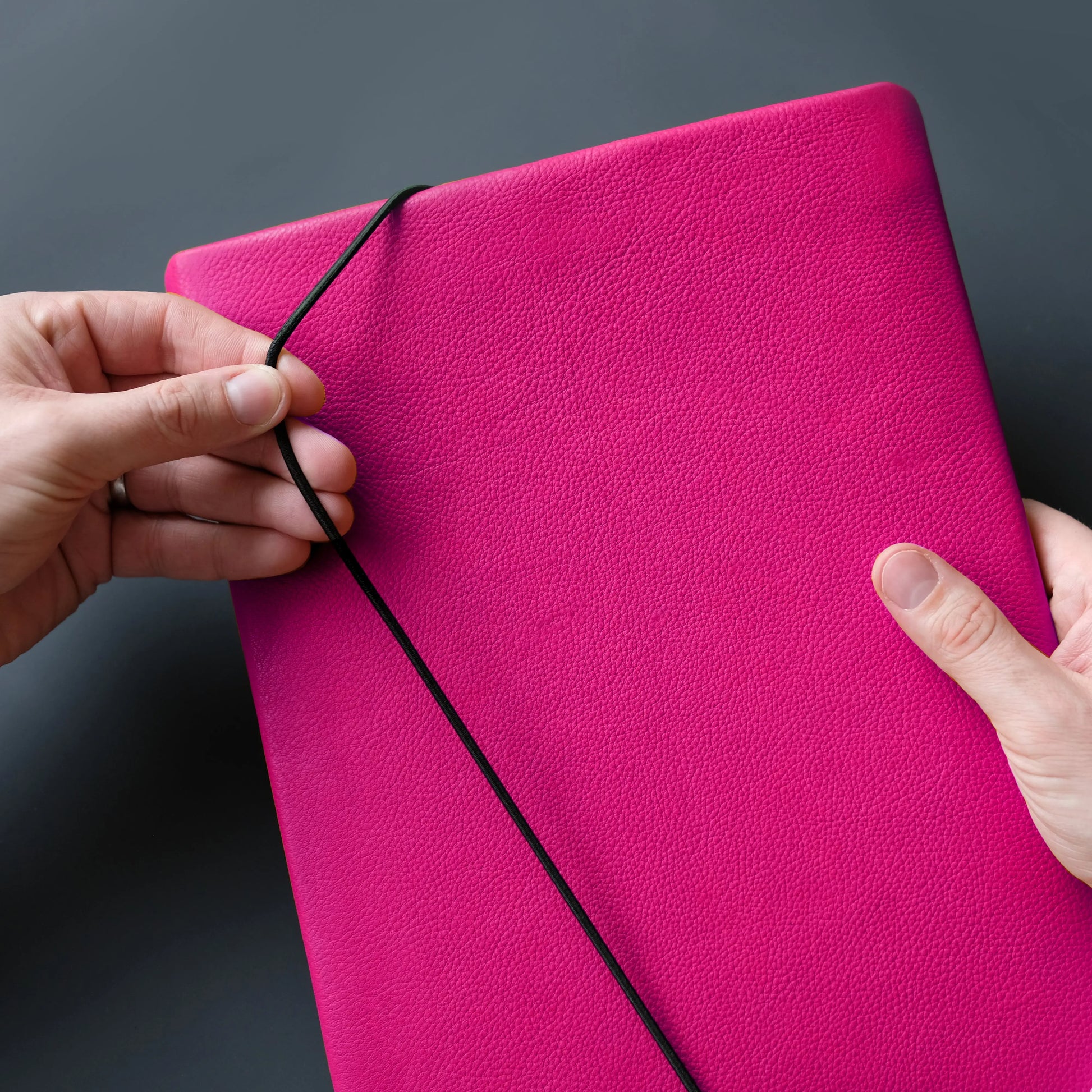 Lederhülle für iPads in neonpink wird mit Verschlussgummi geschlossen
